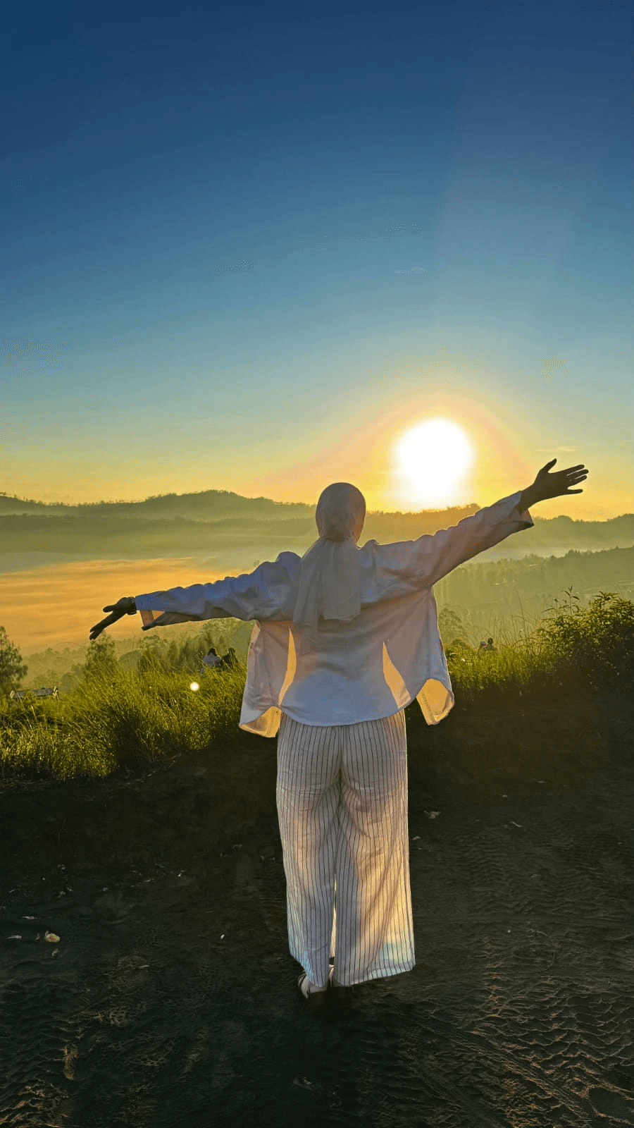 Traveler watching the sunrise over Mount Batur, arms wide